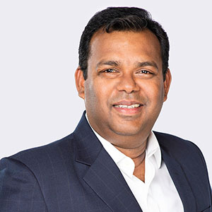 Headshot of South Asian man behind gray background